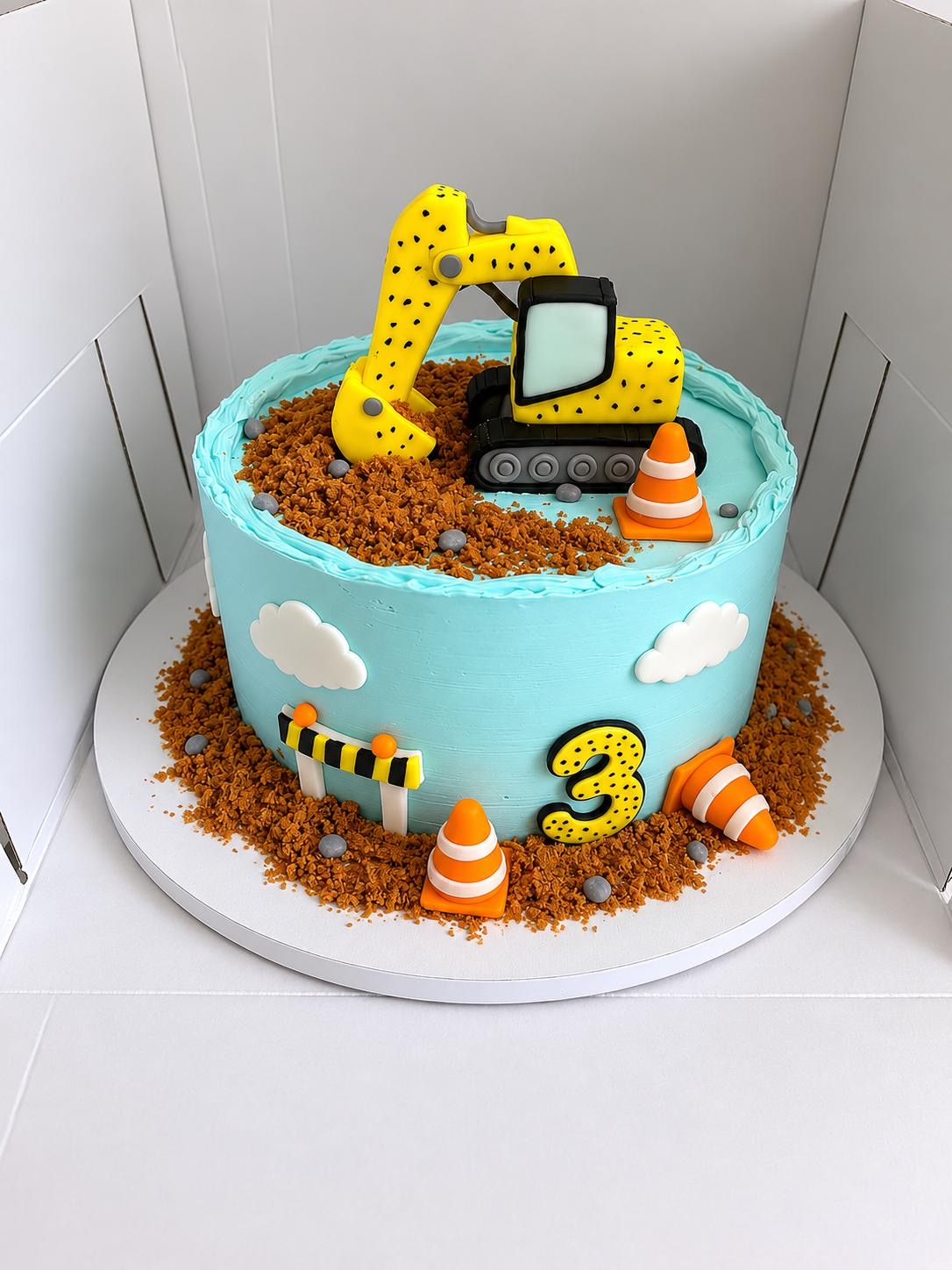Turquoise children’s cake with a modelled yellow excavator and traffic cones